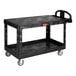 A black Rubbermaid® plastic utility cart with two flat shelves and wheels.