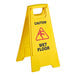 A yellow plastic caution wet floor sign with red text.
