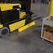A yellow forklift parked against a yellow Vestil steel floor safety curb.