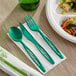 A green Stalk Market compostable fork and knife on a white napkin.