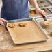 A woman holding a Baker's Lane parchment paper lined sheet pan of cookies.