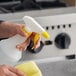 A hand using a Lavex spray bottle to clean a professional kitchen counter.