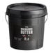 A black Vor macadamia nut butter 8 lb. pail with a lid on a counter.