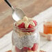 A spoon with a black handle in a jar of macadamia nut butter with a white label.