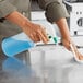 A person using a Lavex green and white sprayer to clean a counter.