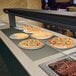 A Hatco built in heated shelf with pizzas on plates.