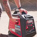 A man with tattoos on his arm pushing a Tomahawk portable inverter generator.