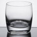 A close up of a Reserve by Libbey Symmetry Rocks glass with a small amount of liquid in it.