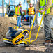 A person wearing a yellow reflective vest using a Tomahawk plate compactor.