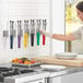 A woman using Fourté stainless steel scalloped tongs with color coated handles in a professional kitchen.