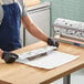 A person in a blue apron cutting a piece of Choice Fresh Catch Butcher Paper.