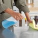 A person spraying a yellow Lavex plastic bottle over a counter.