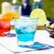 A Libbey Endeavor old fashioned glass with blue liquid and ice with lime slices.