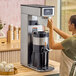 A woman in an apron using a Bunn Infusion Single Tea Brewer to make tea.