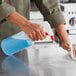 A person using a Lavex red plastic spray bottle to clean a surface.