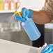 A person wearing blue gloves spraying a Lavex plastic bottle on a counter.