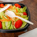 A salad with a cornstarch spork in a plastic container.