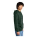 A person wearing a forest green District hoodie with a zipper.