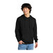 A man in a black District sweatshirt with a hood smiling.