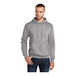 A man wearing a Port & Company Core Fleece grey pullover hoodie with a drawstring.