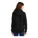 A woman wearing a black Port & Company Core Fleece pullover hoodie.
