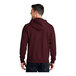 A man wearing a Port & Company maroon full-zip hoodie with the hood up.