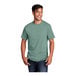 A man smiling and wearing an extra large Port & Company laurel green short sleeve t-shirt.