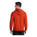 A man wearing an orange Port & Company full-zip hoodie.