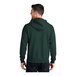 A man wearing a dark green Port & Company full-zip hoodie with the hood up.