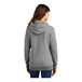 A woman wearing a Port & Company athletic heather grey core fleece pullover hoodie.