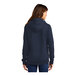 A woman wearing a navy Port & Company Core Fleece pullover hoodie.