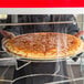 A person holding a pizza in a pizza box on a countertop.