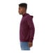 A person wearing a maroon Bella + Canvas sponge fleece pullover hoodie.