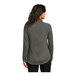 A woman wearing a Port Authority grey quarter-zip sweatshirt.