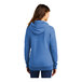 A woman wearing a heather royal blue Port & Company Core Fleece pullover hoodie.