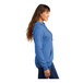 A woman wearing a Port & Company heather royal blue core fleece pullover hoodie.