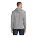 A person wearing a Port & Company athletic heather grey core fleece pullover hoodie with a hood.