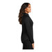 A woman wearing a Port Authority black quarter-zip sweatshirt.