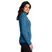 A woman wearing a medium blue Port Authority fleece sweater.