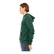 A person wearing a Bella + Canvas heather forest green full-zip hoodie.