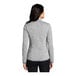 A woman wearing a gray Port Authority fleece sweater jacket.