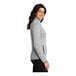 A woman wearing a Port Authority gray fleece sweater jacket.