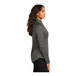 A woman wearing a Port Authority grey quarter-zip sweatshirt.