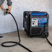 A man using a power cord to start a DuroMax portable generator outdoors.