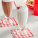 Two Acopa soda glasses filled with milkshakes topped with whipped cream and cherries.