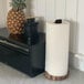 An Ironwood Gourmet acacia wood paper towel holder with a leather handle on a black counter next to a pineapple.