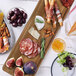 An Ironwood acacia wood shovel paddle board with various types of food on it.