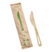 A compostable bamboo knife with a serrated edge, shown next to its eco-friendly paper packaging.