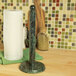 An Ironwood Gourmet green marble paper towel holder on a kitchen counter next to a roll of paper towels.