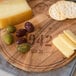An Ironwood acacia wood serving board with wine barrel engraving holding cheese and crackers.